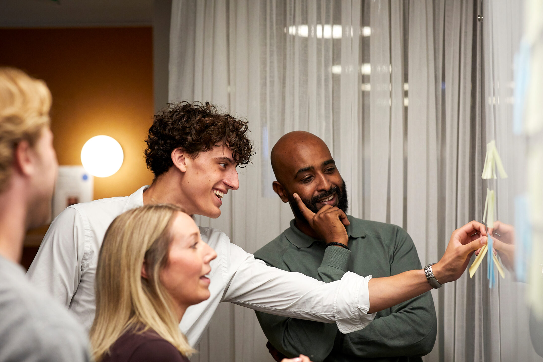 Three colleagues adding notes to a glass planning board