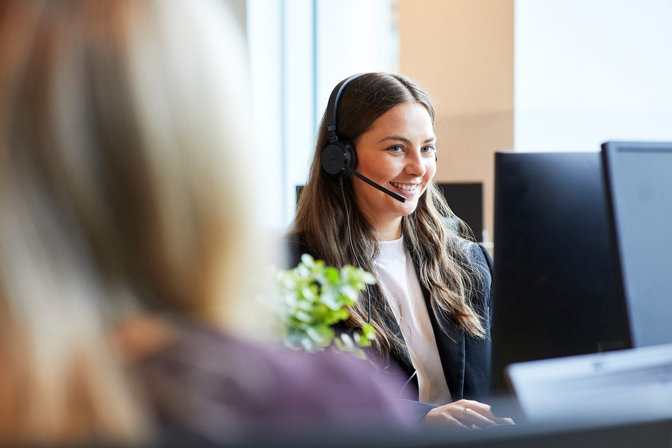 A colleague wearing a headset smiling at her screen
